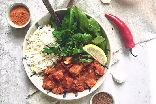 Quorn Vegan Masala Curry, made with Quorn Vegan Pieces, onion, turmeric, paprika, chilli, served with rice, lettuce and lemon in a bowl.