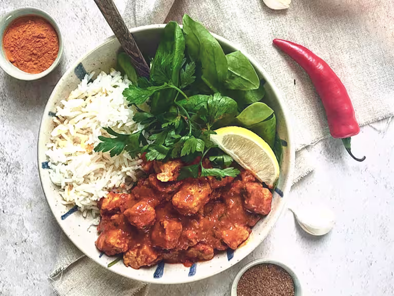Quorn Vegan Masala Curry, made with Quorn Vegan Pieces, onion, turmeric, paprika, chilli, served with rice, lettuce and lemon in a bowl.