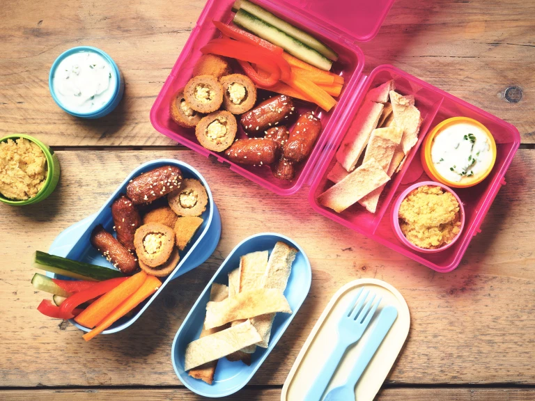 Mezze of Quorn Cocktail Sausages and Mini Savoury eggs served in colourful Tupperware with vegetables, pitta and pots of sauce