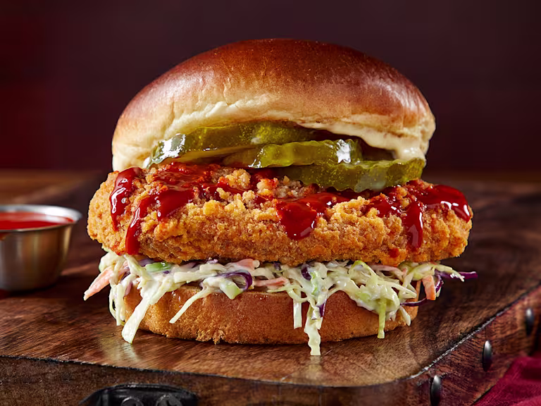 Vegetarian ChiQin Sandwich on a wooden slate with hot sauce