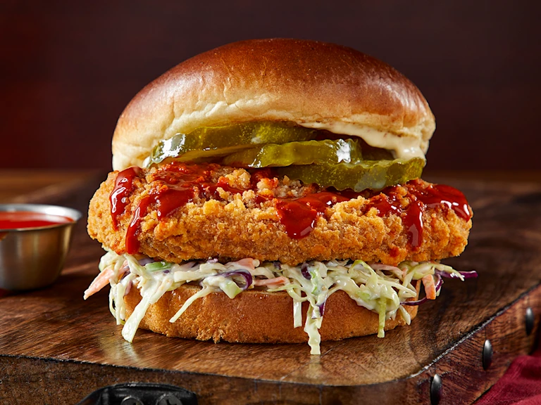 Vegetarian ChiQin Sandwich on a wooden slate with hot sauce