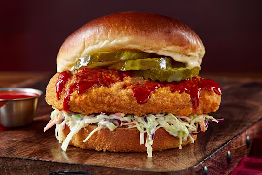 Vegetarian Chicken Sandwich on a wooden slate with hot sauce