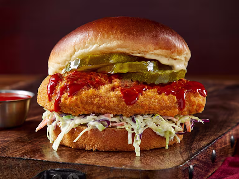 Vegetarian Chicken Sandwich on a wooden slate with hot sauce