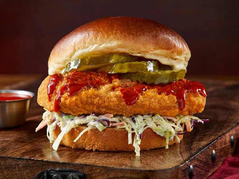 Vegetarian Chicken Sandwich on a wooden slate with hot sauce 