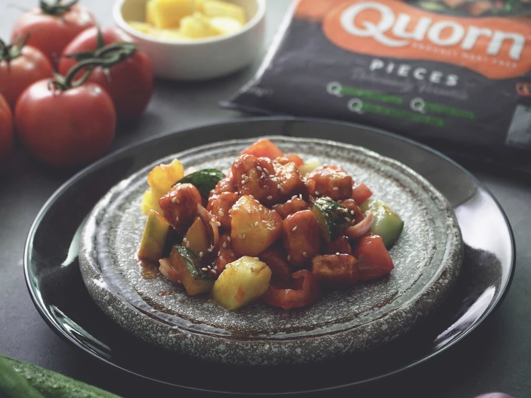 Sweet and sour Quorn Pieces with pineapple and peppers, dressed with sesame seeds on a plate dressed with sesame seeds
