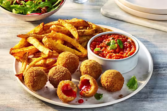 Air Fryer Veggie Chicken Balls with one split open to show the filling, served alongside roasted red pepper dip and fries.
