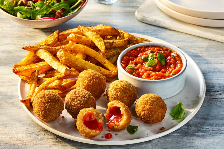 Air Fryer Veggie Chicken Balls with one split open to show the filling, served alongside roasted red pepper dip and fries.