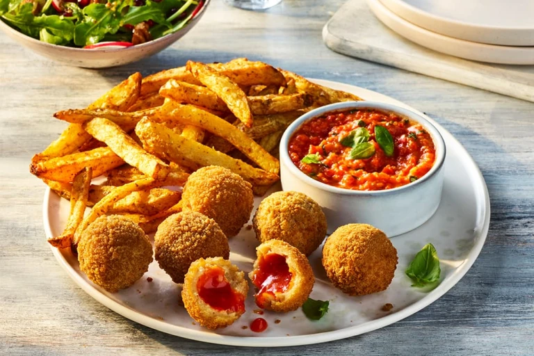 Air Fryer Veggie Chicken Balls with one split open to show the filling, served alongside roasted red pepper dip and fries.