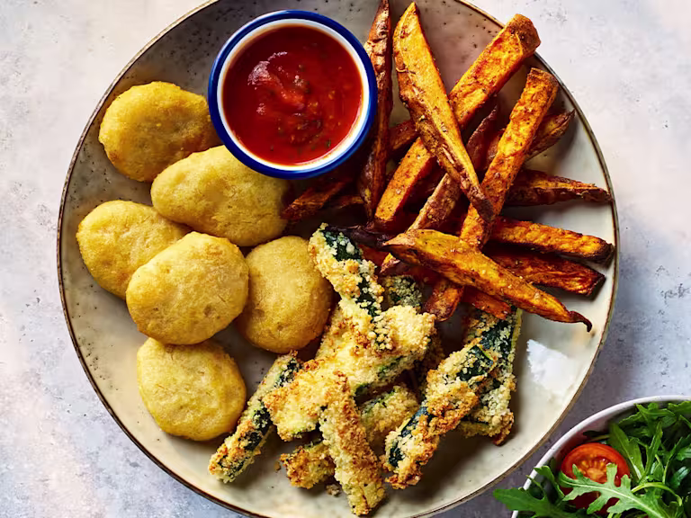 Quorn Meatless ChiQin Nuggets with parmesan and garlic zucchini chips on a board with sauce and salad on the side