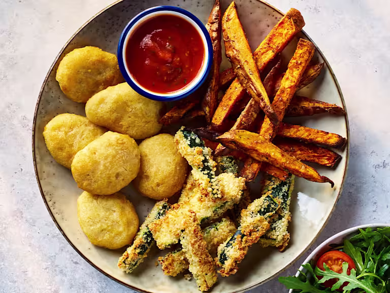 Quorn crispy nuggets with parmesan and garlic courgette chips on a board with sauce and salad on the side