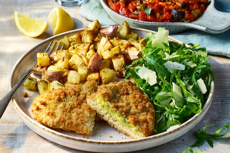 Quorn Pesto And Mozzarella Meatless ChiQin Cutlets with potatoes and arugula topped with topped with parmesan on a light dish. 