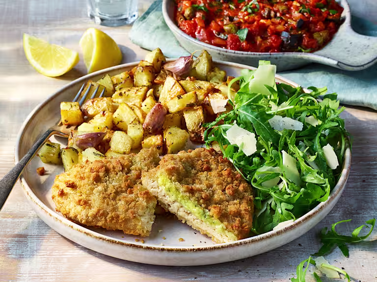 Quorn Pesto And Mozzarella Meatless ChiQin Cutlets with potatoes and arugula topped with topped with parmesan on a light dish.