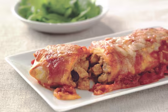 Vegetarian enchiladas made with Quorn Pieces, beans and cheese, sliced to reveal the centre, served on a white plate