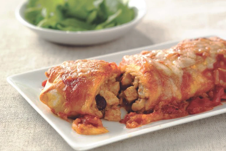 Vegetarian enchiladas made with Quorn Pieces, beans and cheese, sliced to reveal the centre, served on a white plate