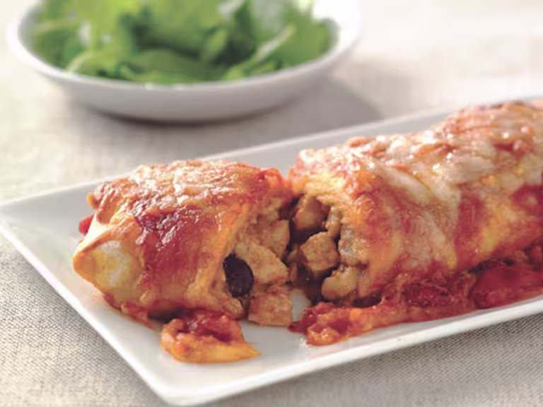 Vegetarian enchiladas made with Quorn Pieces, beans and cheese, sliced to reveal the centre, served on a white plate