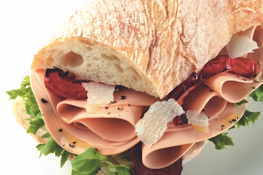 Sandwich made with Quorn Vegetarian Ham Slices on top of lettuce, dressed with parmesan and sundried tomato served in ciabatta