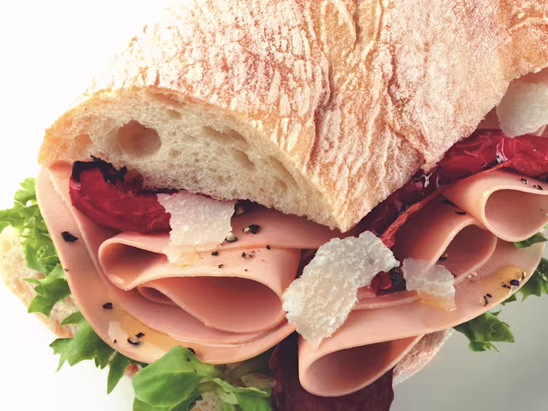Sandwich made with Quorn Vegetarian Ham Slices on top of lettuce, dressed with parmesan and sundried tomato served in ciabatta