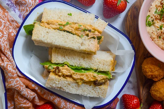 Vegetarian sandwich sliced in half facing upwards served in a white dish.
