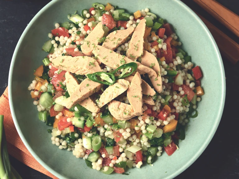 A bowl of giant couscous zingy chili and lime salad with Quorn Roasted Sliced Fillets.