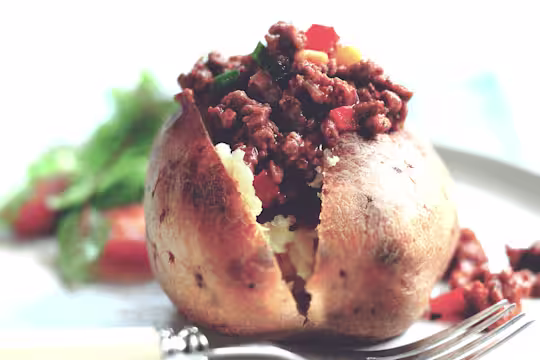 A jacket potato sliced to show the vegetarian chilli made using Quorn Vegetarian Mince.
