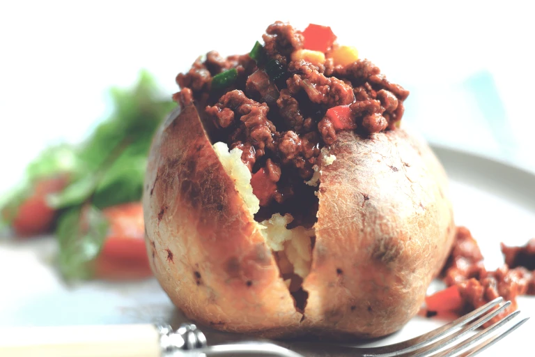 Meat free jacket potato recipe topped with Quorn Mince, tomato and kidney beans, garnished with diced peppers served on a plate