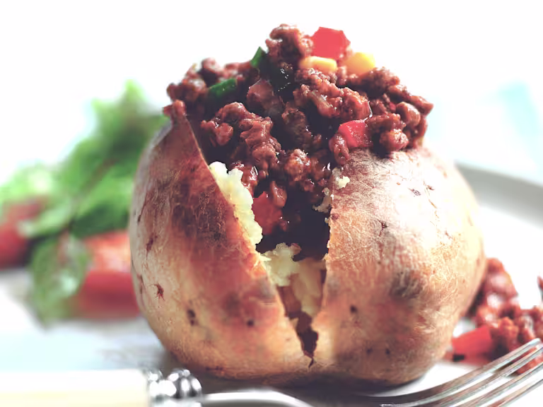 A jacket potato sliced to show the vegetarian chilli made using Quorn Vegetarian Mince.