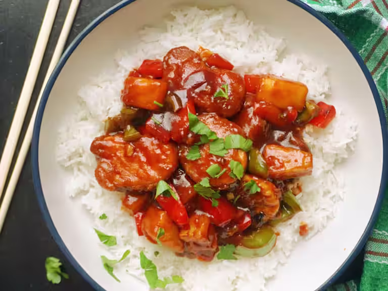 Vegetarian Sweet And Sour with Quorn Crispy Nuggets served on a bed of rice with chopsticks on the side.