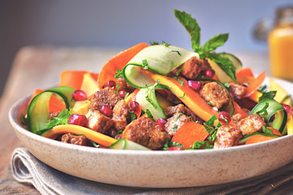A salad with ribbons of cucumber, papaya, and carrots topped with mint, pomegranate seeds, and Quorn Pieces.