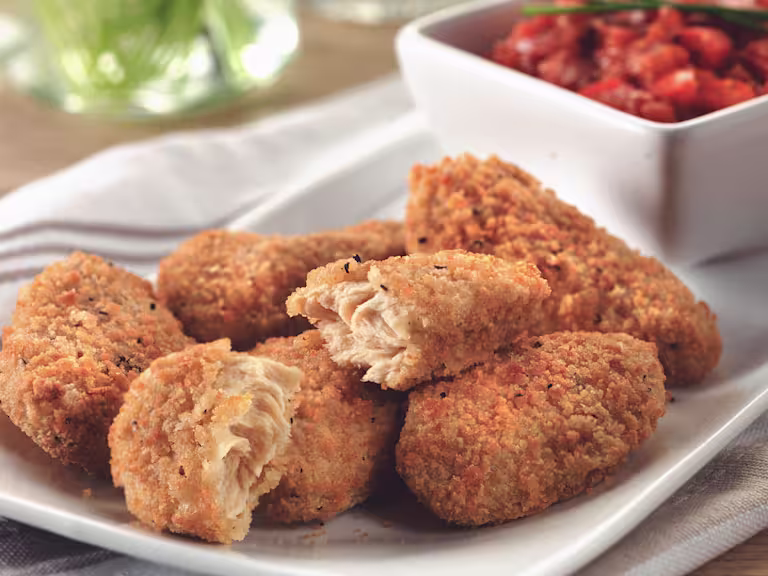 Quorn Southern Fried Bites on a white plate with a dish of red pepper relish in the background.