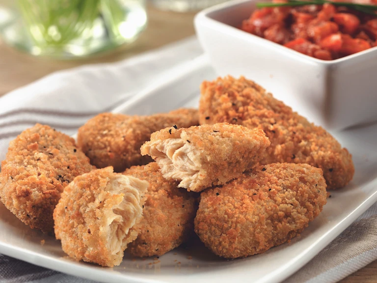 Quorn Southern Fried Bites on a white plate with a dish of red pepper relish in the background.