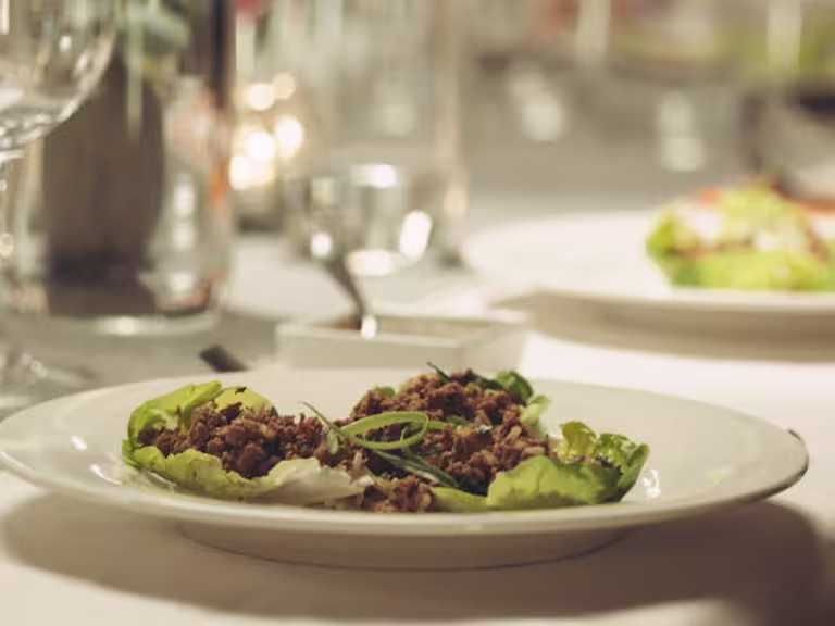 Two lettuce cups filled with a Quorn Mince laab salad on a white plate.