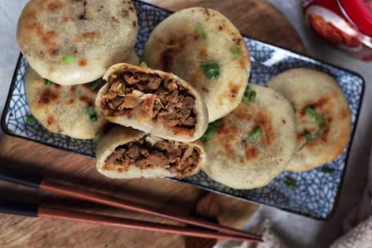 Six vegetarian air fryer kimchi buns arranged on a plate with one halved to reveal a filling of Quorn Mince and kimchi.
