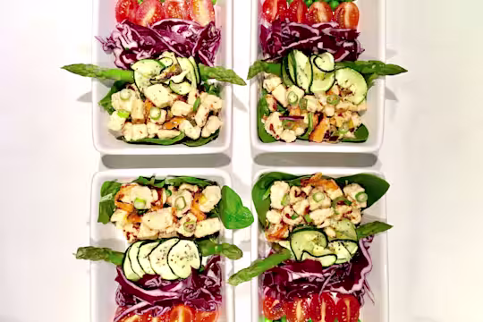 Meal prep idea of Quorn Pieces on top of asparagus, spinach, courgette and red cabbage, topped with chopped spring onion