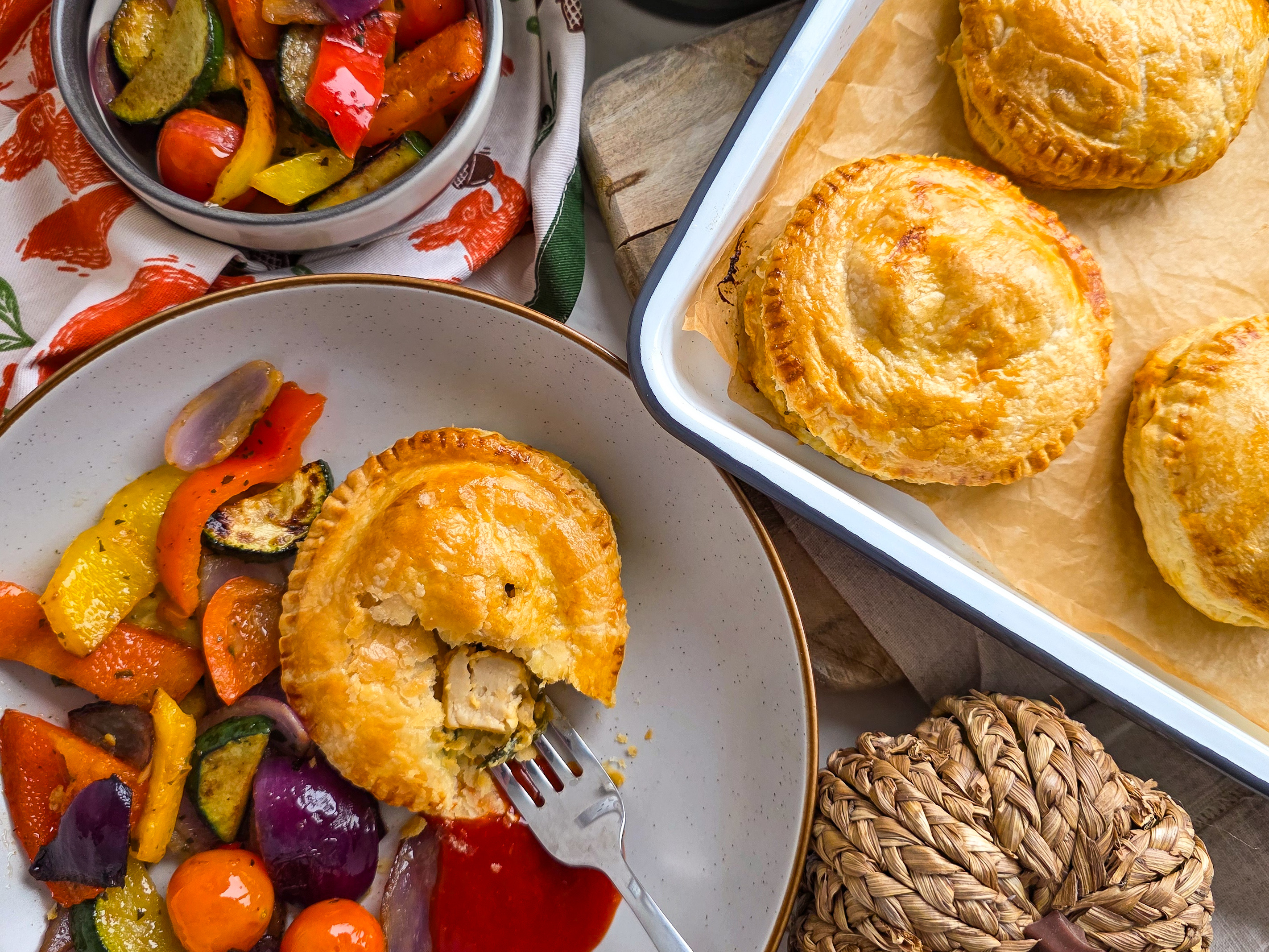 A Veggie Chicken & Cheese Pie in a white bowl with peppers, tomatoes and roasted vegetables.