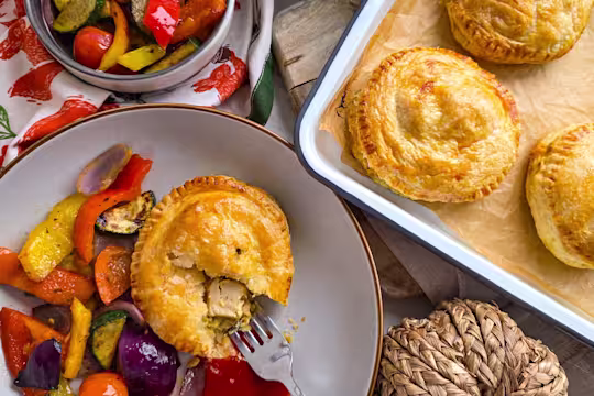 A Veggie Chicken & Cheese Pie in a white bowl with peppers, tomatoes and roasted vegetables.