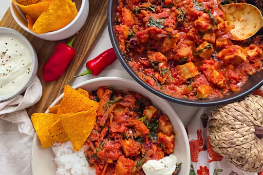 Vegetarian Chicken Chilli in a white bowl with rice and Tortilla chips.
