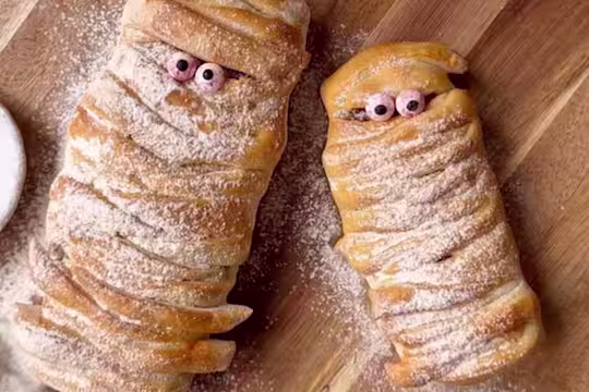 Strips of pizza dough wrapped in a mummy shape with googly eyes and dusted with flour.