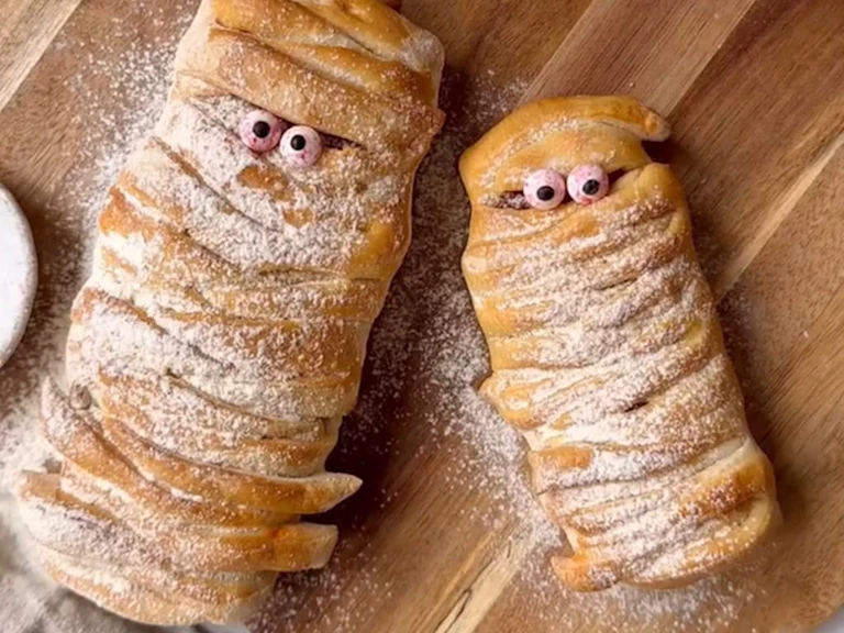 Strips of pizza dough wrapped in a mummy shape with googly eyes and dusted with flour.