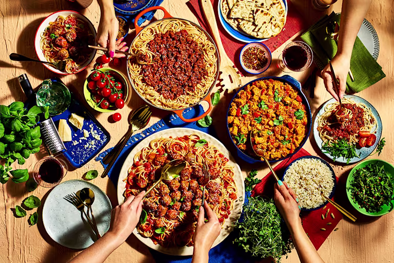 Various recipes with hand reaching out to take a bite, dishes include; vegetarian meatballs and spaghetti, vegetarian curry rice and more.