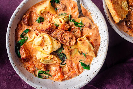 Vegetarian sausage and tortellini soup served in a white bowl with Quorn Cocktail Sausages on the side.