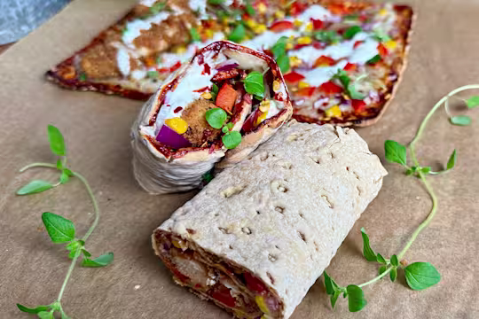 Vegetariska pizzarullar gjorda på tunnbröd, fyllda med Quorn Salt & Pepper Tenders, paprika, rödlök, majs och ost, toppade med färsk oregano. I bakgrunden syns en platt pizza med samma fyllning på bakplåtspapper.