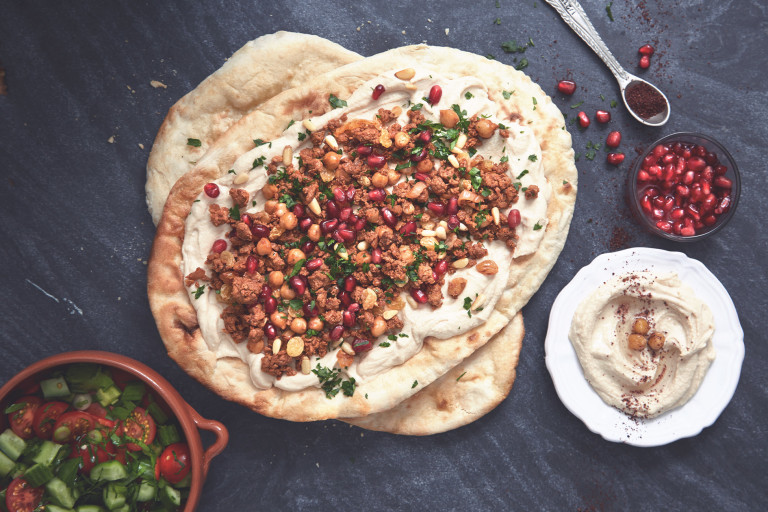 Healthy flatbread layered with Quorn Mince dressed with pomegranate seeds and chopped parsley with a side of hummus