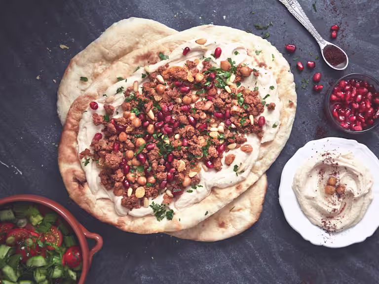 Healthy flatbread layered with Quorn Mince dressed with pomegranate seeds and chopped parsley with a side of hummus