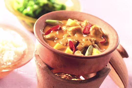 Vegetarian Thai red curry made with Quorn Pieces, peppers and mango served in a ceramic dish next to a bowl of rice