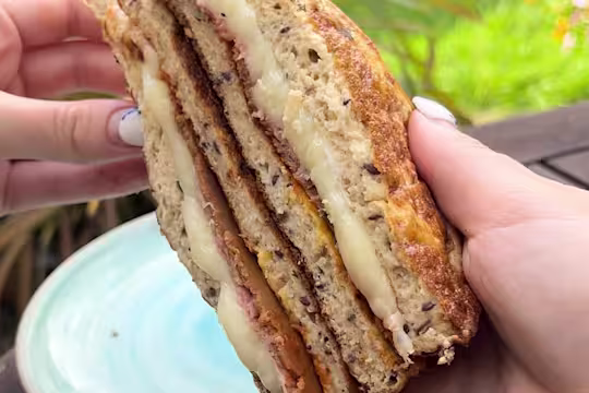 Somebody holding a cheese toastie with Quorn Roast Beef and Finely Sliced Ham Style Slices