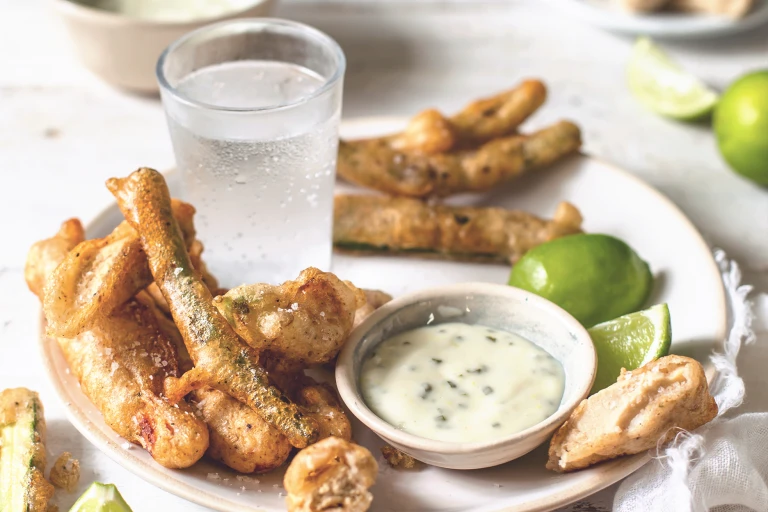 Tempura-battered Quorn Vegetarian Fillets, courgettes, green beans, and edible flowers arranged on a plate with mayonnaise dipping sauce on the side.