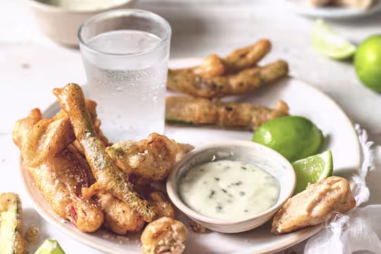 Tempura-battered Quorn Vegetarian Fillets, courgettes, green beans, and edible flowers arranged on a plate with mayonnaise dipping sauce on the side.
