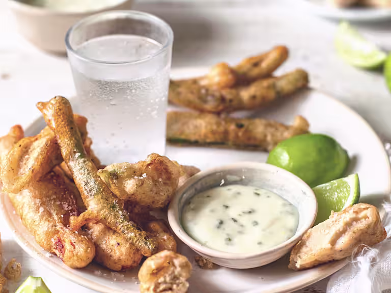 Tempura-battered Quorn Vegetarian Fillets, courgettes, green beans, and edible flowers arranged on a plate with mayonnaise dipping sauce on the side.