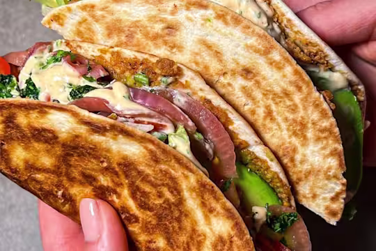 Two veggie Smashburger tacos held in someone’s hand with the filling visible.