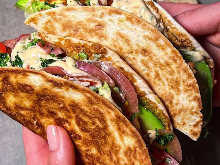 Two veggie Smashburger tacos held in someone’s hand with the filling visible.